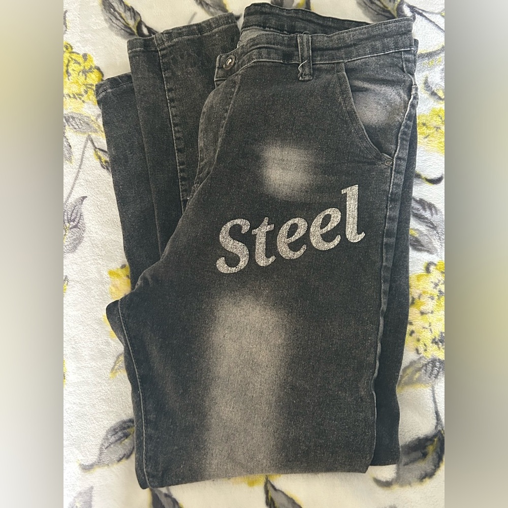 AMIRI men’s black distressed jeans with “Steel” wording in the front!